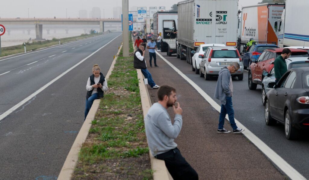 Un grupo de personas en una calle con coches.