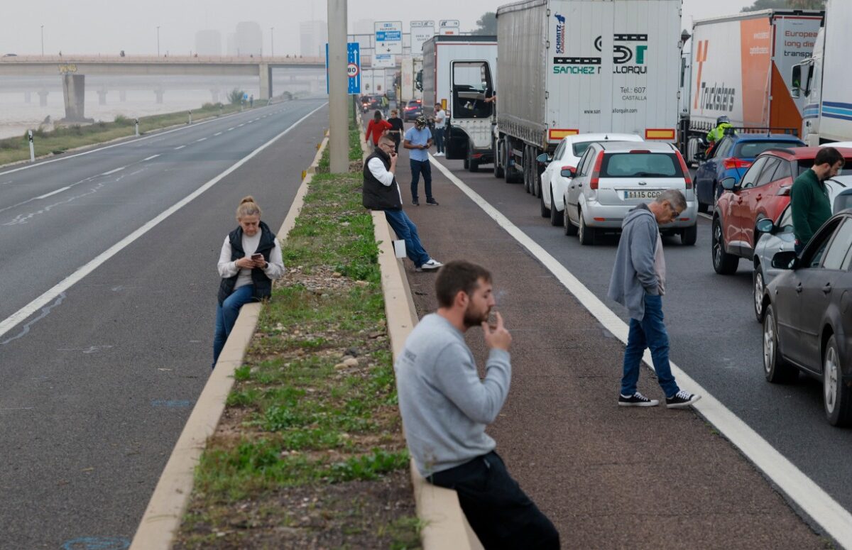 Un grupo de personas en una calle con coches.