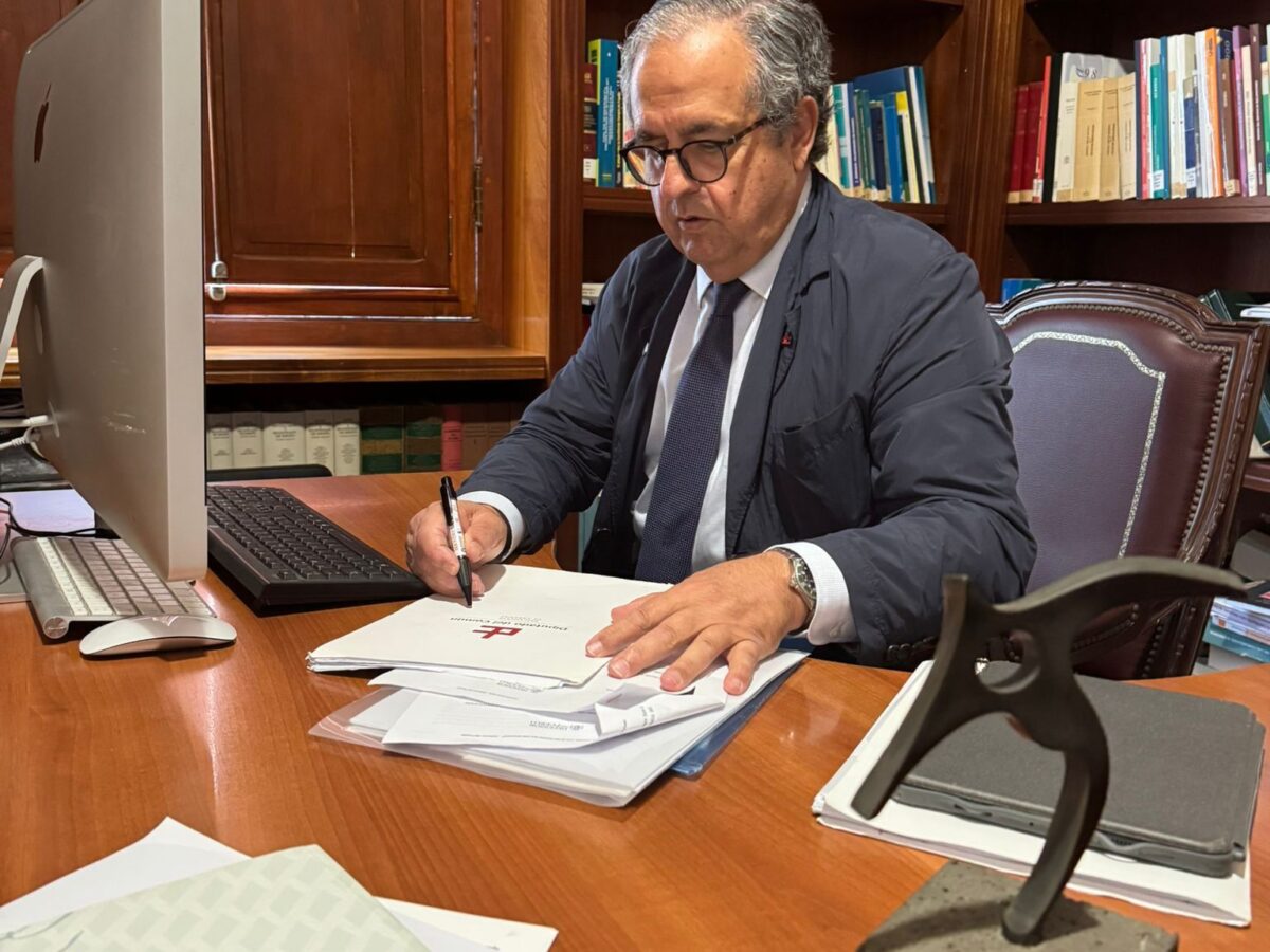 Mujer mayor sentada en un escritorio.