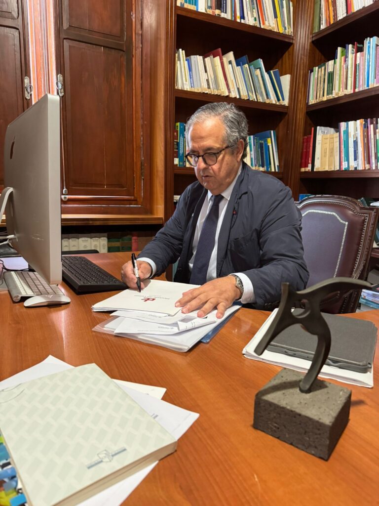 Mujer mayor sentada en un escritorio.