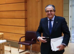 Una persona en traje parado enfrente de una mesa.